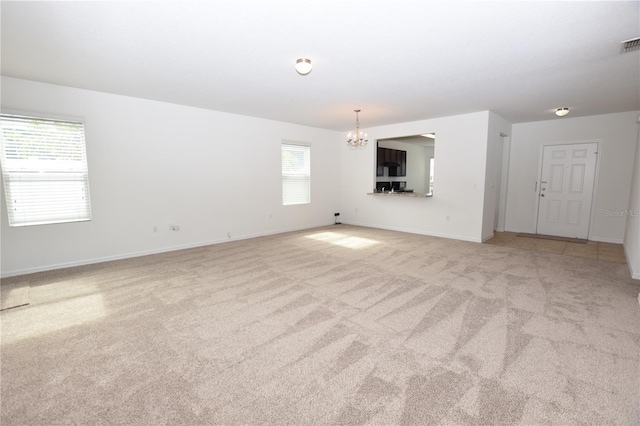 unfurnished living room with light carpet and a chandelier