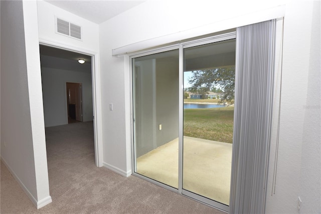 doorway featuring light colored carpet and a water view