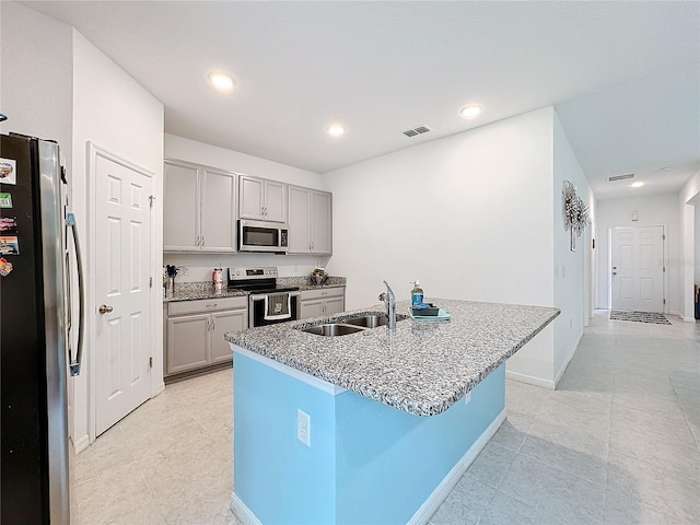 kitchen featuring gray cabinets, stainless steel appliances, a kitchen island with sink, and sink