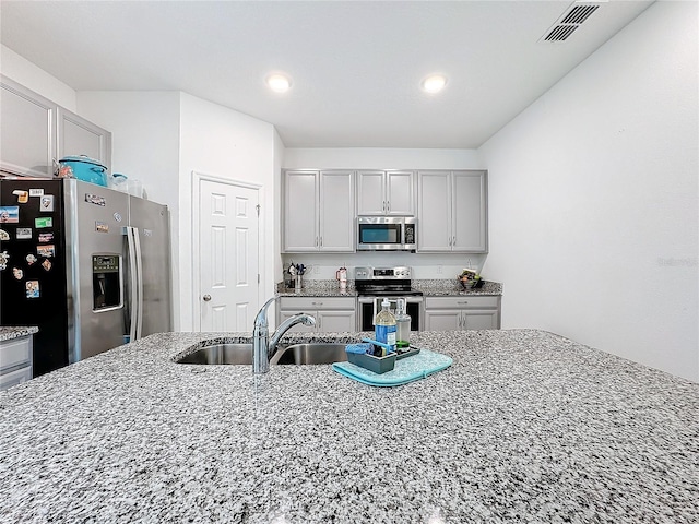 kitchen featuring light stone counters, sink, appliances with stainless steel finishes, and gray cabinets