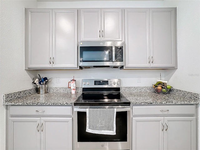 kitchen with white cabinets, light stone countertops, and stainless steel appliances