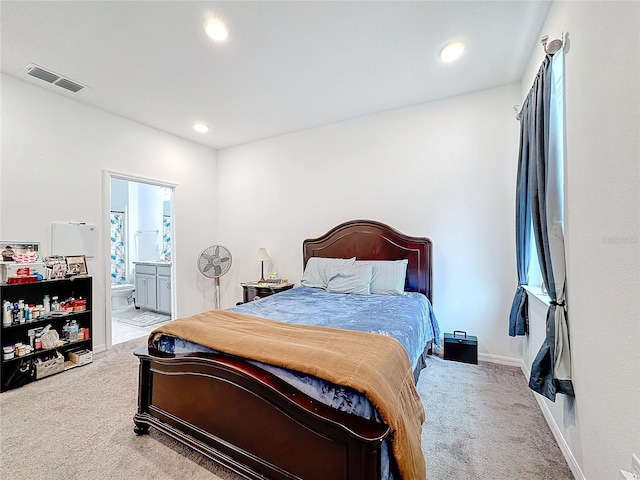 bedroom with light colored carpet and ensuite bath