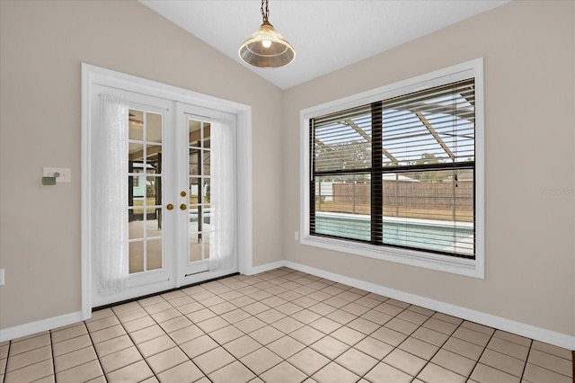 tiled empty room with lofted ceiling and french doors