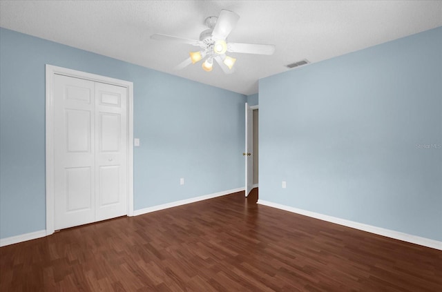 unfurnished bedroom with dark wood-type flooring, ceiling fan, a closet, and a textured ceiling