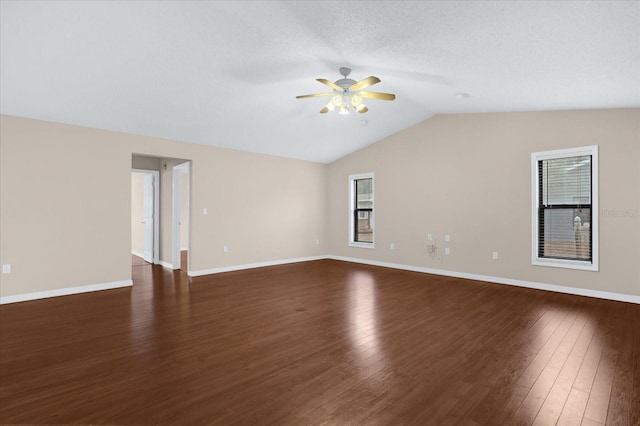 spare room with ceiling fan, vaulted ceiling, dark wood-type flooring, and plenty of natural light