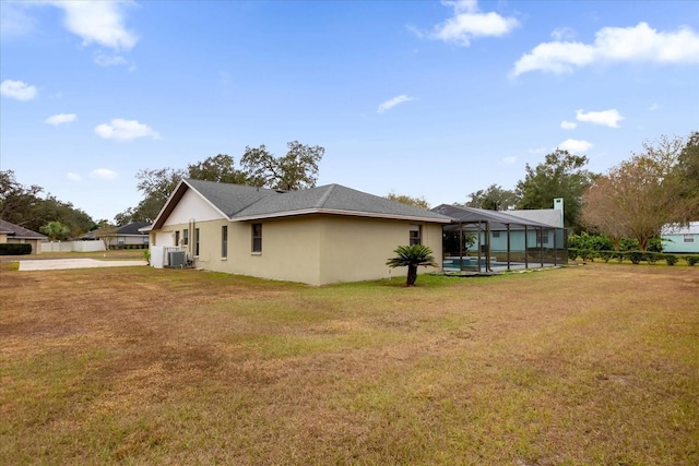 view of home's exterior featuring glass enclosure, a swimming pool, a lawn, and central air condition unit