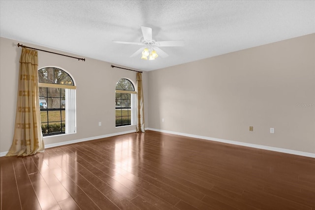 unfurnished room with a textured ceiling, ceiling fan, a wealth of natural light, and dark hardwood / wood-style flooring