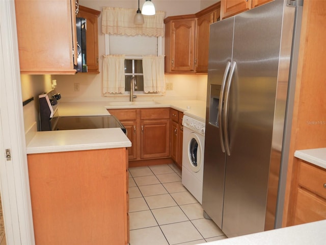 kitchen with light tile patterned floors, a sink, light countertops, appliances with stainless steel finishes, and washer / dryer