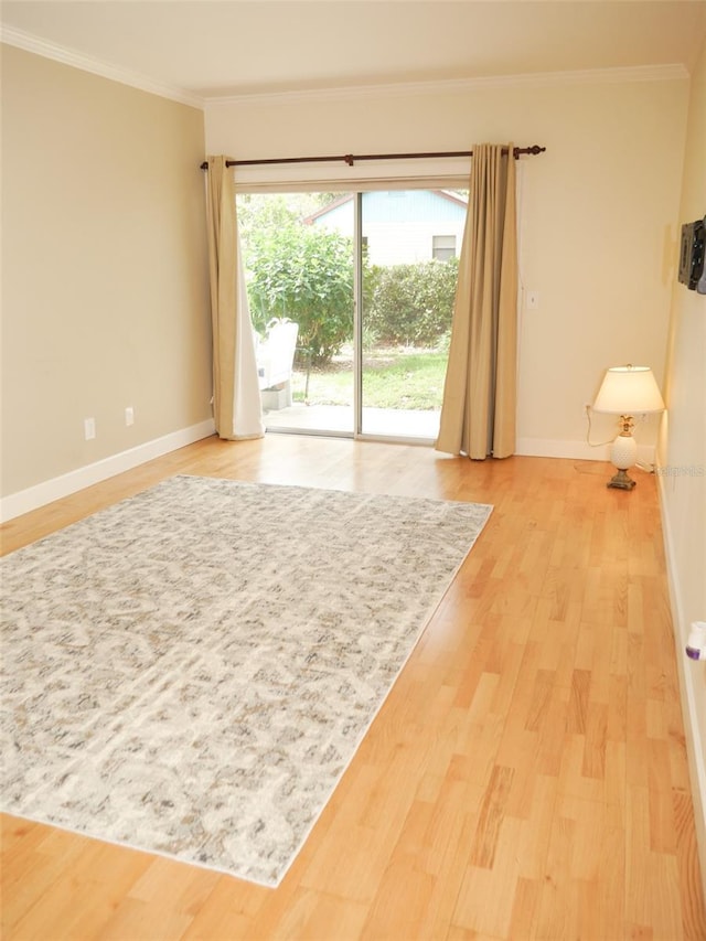 empty room featuring ornamental molding, wood finished floors, and baseboards