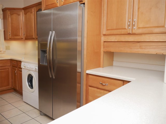 kitchen featuring light tile patterned floors, light countertops, washer / clothes dryer, and stainless steel fridge