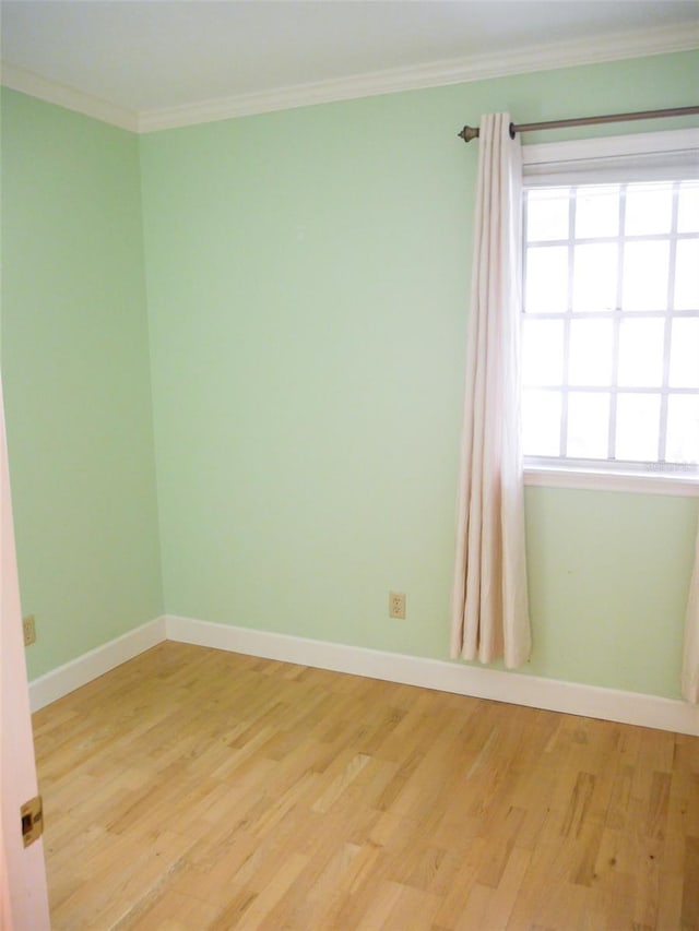 unfurnished room with light wood finished floors, baseboards, and ornamental molding