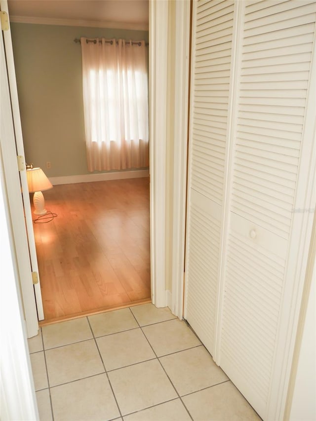 hallway featuring ornamental molding, baseboards, and light tile patterned floors