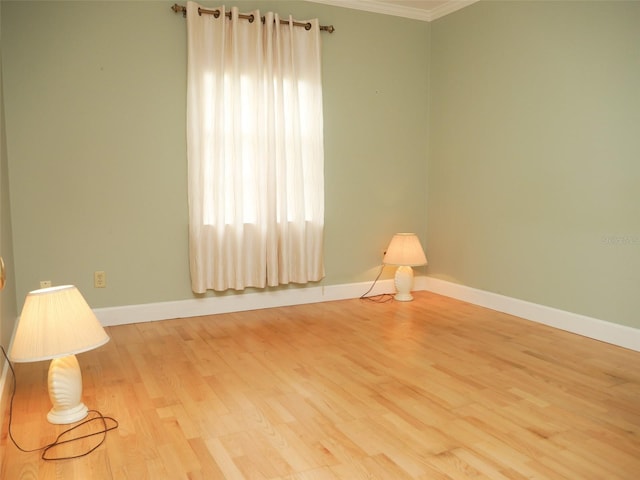 unfurnished room with light wood-style floors, ornamental molding, and baseboards