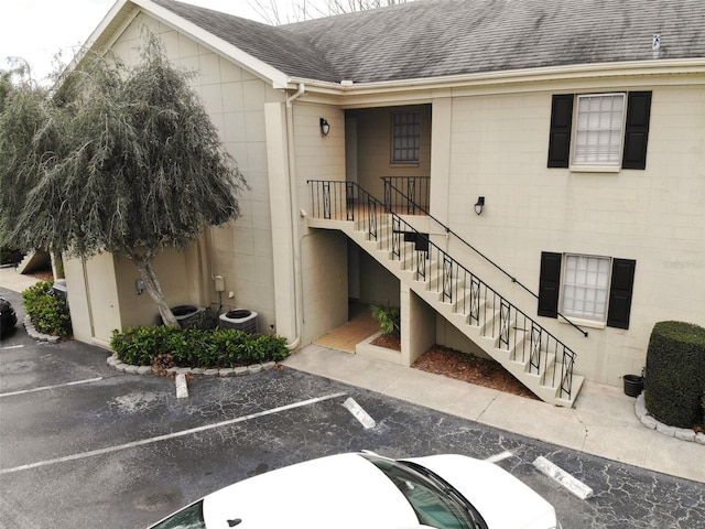 view of building exterior with stairs and uncovered parking