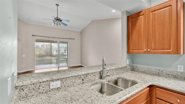 kitchen featuring sink, crown molding, vaulted ceiling, ceiling fan, and light stone countertops