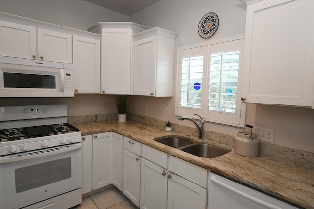 kitchen with light stone countertops, white appliances, white cabinetry, sink, and light tile patterned floors