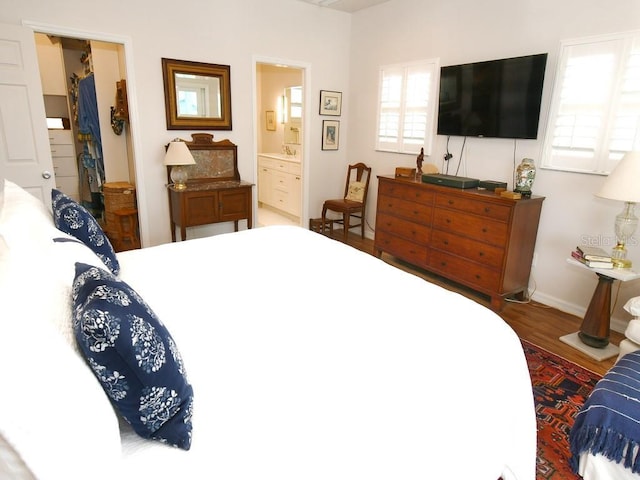 bedroom with connected bathroom and wood-type flooring