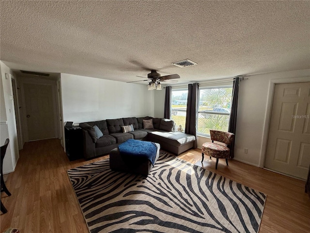 living room featuring a textured ceiling, ceiling fan, and light hardwood / wood-style flooring