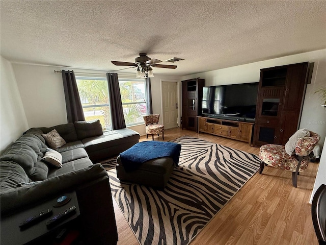 living room with a textured ceiling, ceiling fan, and light hardwood / wood-style flooring