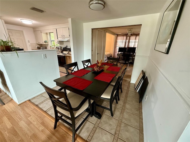 dining space featuring light wood-type flooring and a textured ceiling