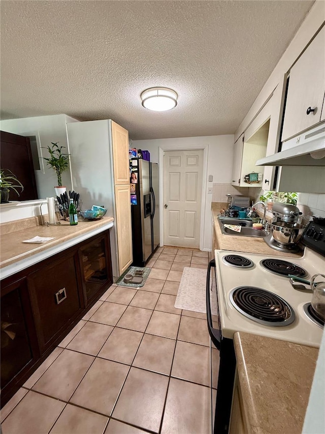 kitchen featuring a textured ceiling, stainless steel refrigerator with ice dispenser, white cabinetry, black / electric stove, and sink