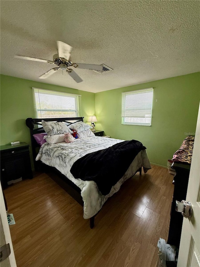 bedroom with a textured ceiling, ceiling fan, and hardwood / wood-style floors