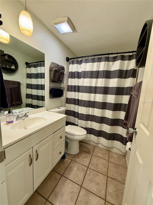 bathroom with a textured ceiling, toilet, vanity, and tile patterned flooring