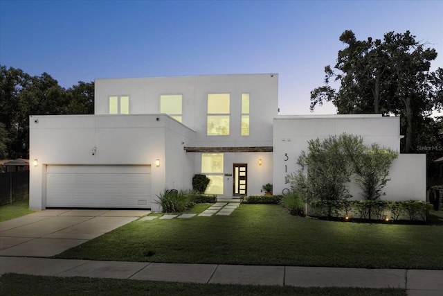 contemporary house featuring a garage and a lawn