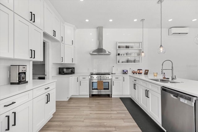 kitchen featuring appliances with stainless steel finishes, hanging light fixtures, wall chimney exhaust hood, white cabinets, and sink