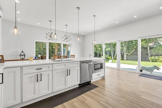 kitchen with sink, pendant lighting, white cabinets, and stainless steel appliances