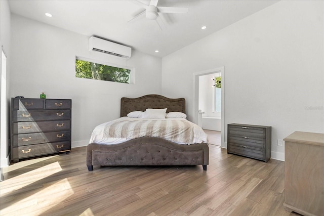 bedroom with hardwood / wood-style floors, ensuite bath, lofted ceiling, a wall unit AC, and ceiling fan