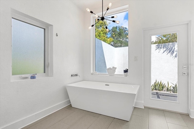 bathroom with a chandelier and a tub