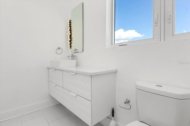 bathroom featuring toilet, a healthy amount of sunlight, tile patterned floors, and vanity