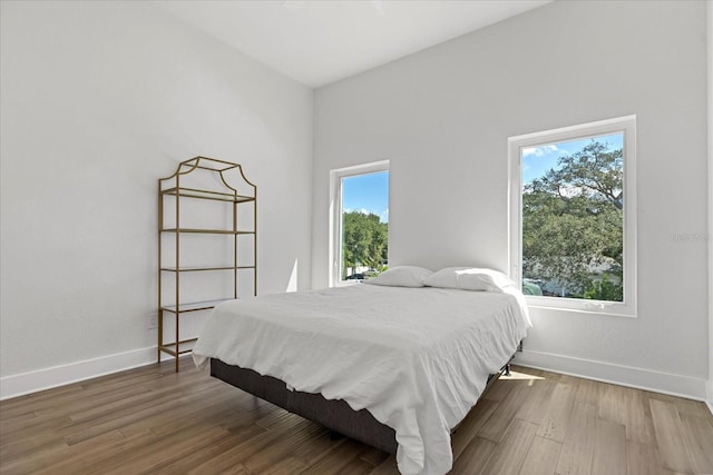 bedroom featuring hardwood / wood-style floors and a towering ceiling