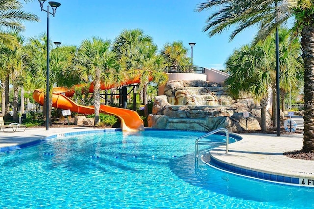 view of swimming pool featuring a playground and a water slide