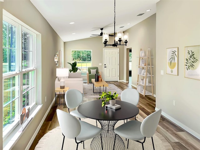 dining room with lofted ceiling, ceiling fan with notable chandelier, and hardwood / wood-style floors