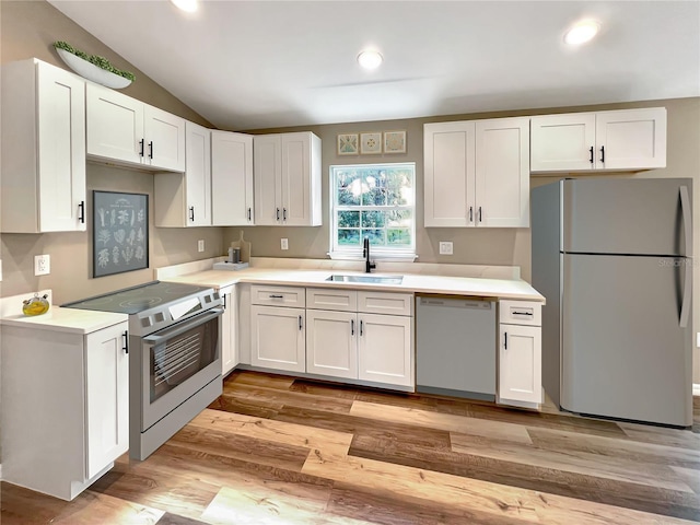 kitchen featuring white cabinetry, stainless steel appliances, sink, vaulted ceiling, and light hardwood / wood-style flooring