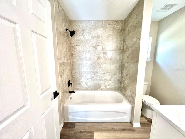 full bathroom featuring toilet, tiled shower / bath, wood-type flooring, and vanity