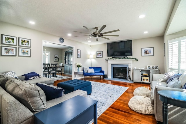 living room featuring a textured ceiling, ceiling fan with notable chandelier, and hardwood / wood-style floors