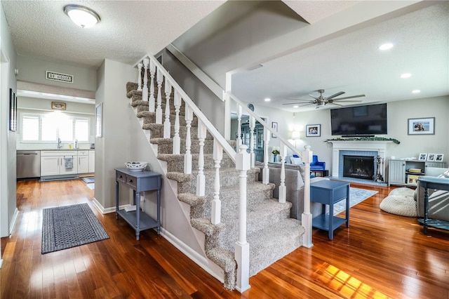 stairs featuring ceiling fan, wood-type flooring, and a textured ceiling