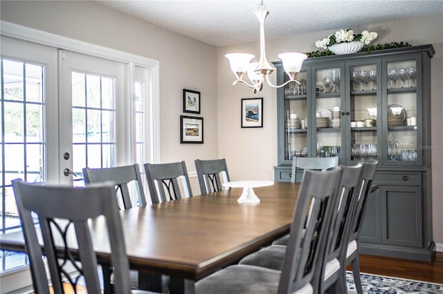 dining room featuring a textured ceiling, an inviting chandelier, and dark wood-type flooring