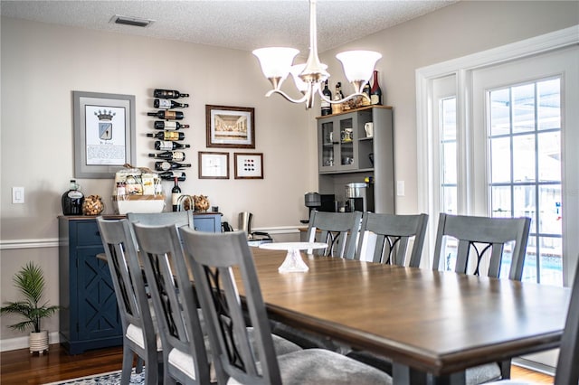 dining area featuring a textured ceiling, dark hardwood / wood-style floors, and a notable chandelier