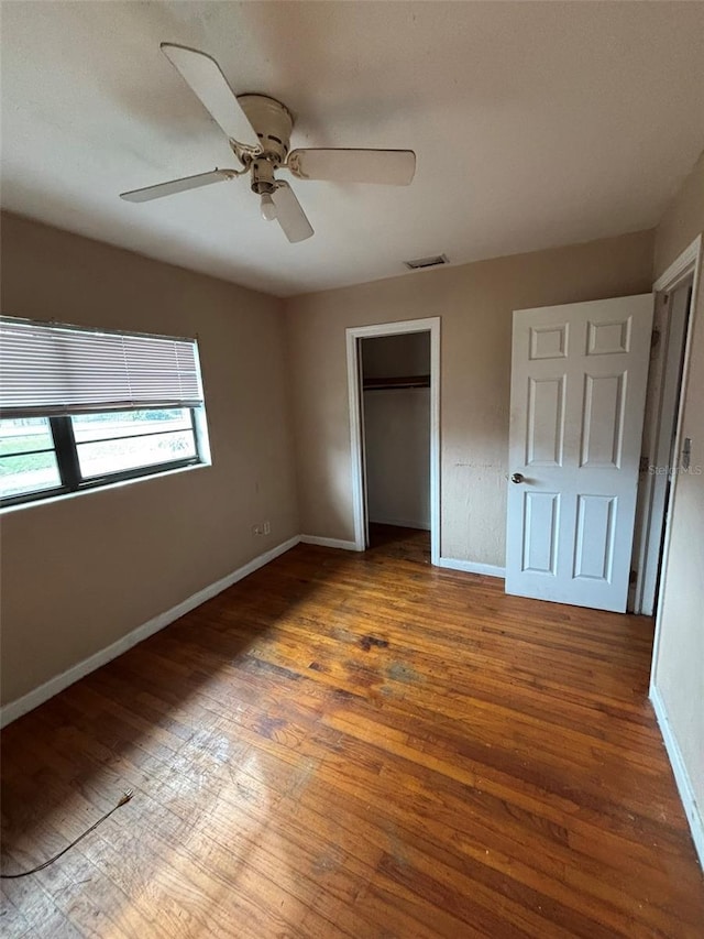 unfurnished bedroom with ceiling fan, dark hardwood / wood-style flooring, and a closet