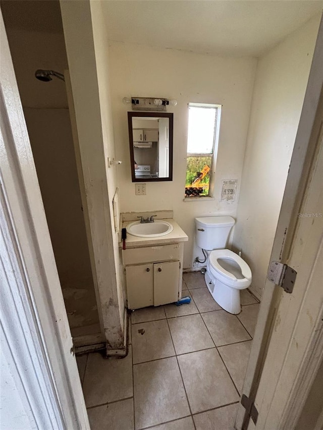 bathroom featuring toilet, tile patterned flooring, walk in shower, and vanity