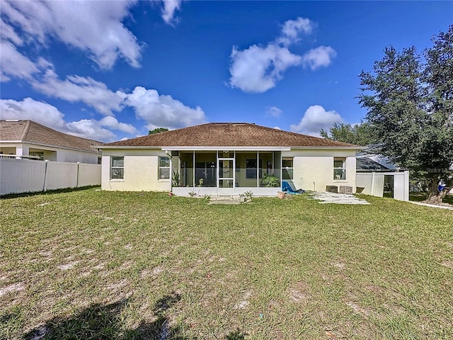 back of house featuring a sunroom, a lawn, and a patio