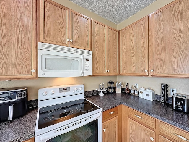 kitchen with a textured ceiling, light brown cabinets, and white appliances