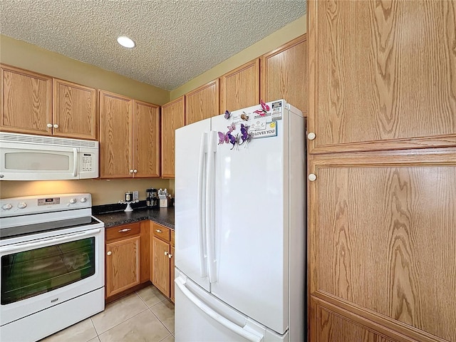 kitchen featuring light tile patterned floors, white appliances, and a textured ceiling