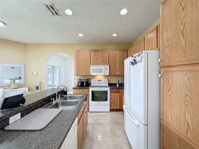 kitchen featuring a textured ceiling, light tile patterned floors, sink, and white appliances