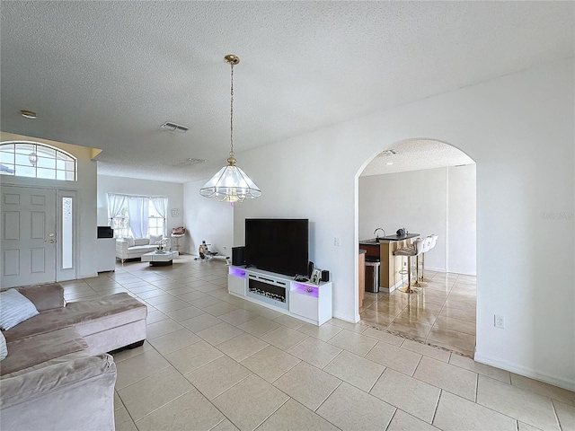 living room featuring a textured ceiling, a notable chandelier, and light tile patterned flooring