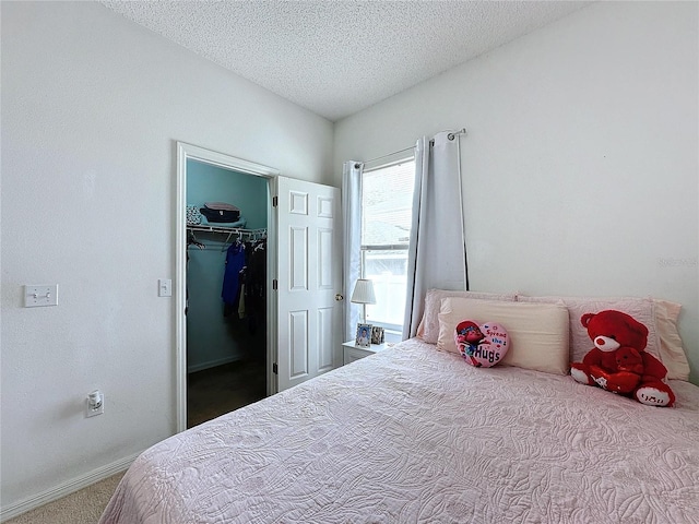 bedroom featuring a spacious closet, a closet, carpet flooring, and a textured ceiling